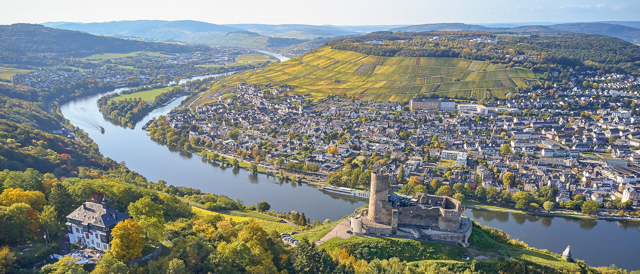 Drohnenbild der Burg Landshut, die auf einem Berg hoch über der Mosel thront. Im Hintergrund die Mosel und der Stadtteil Kues. 