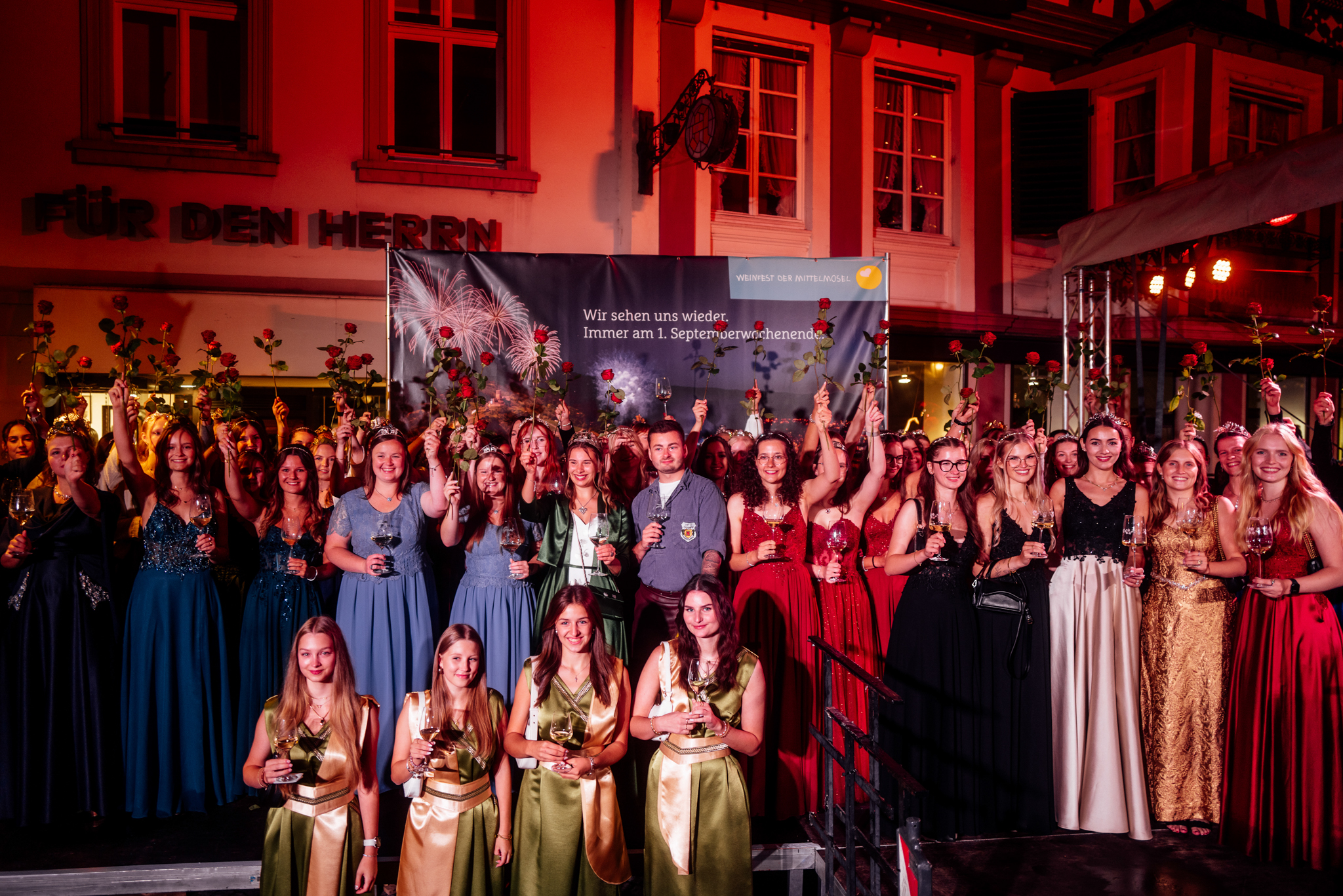 Zahlreiche Weinhoheiten aus den Moselorten stehen beim Weinfest der Mittelmosel in Bernkastel-Kues auf einem Podest und posieren für Fotos. Sie tragen alle schicke Abendkleider.