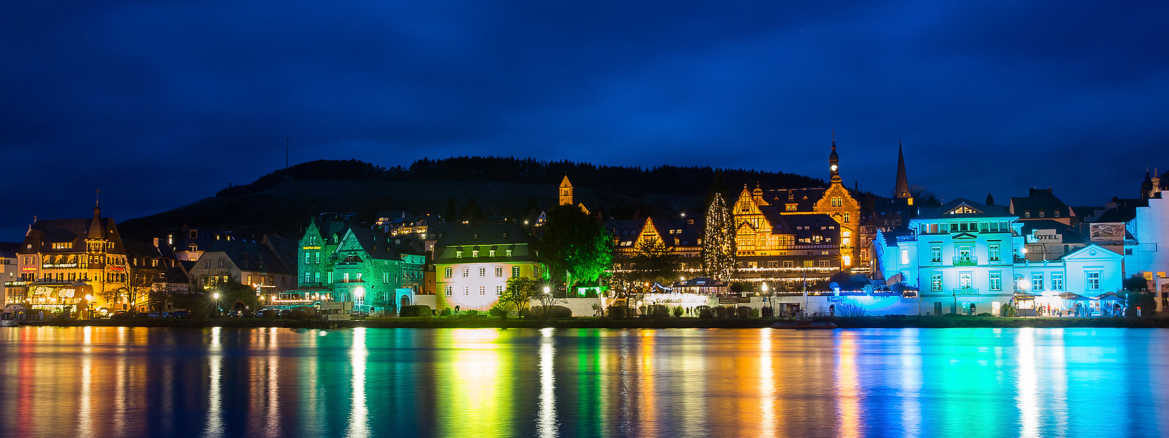 Das Bild zeigt die bunt beleuchtetet Skyline der Moselstadt Traben-Trarbach bei Nacht.